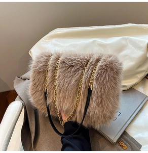 Detail of soft brown faux fur bag with golden metal chain and black leather pad