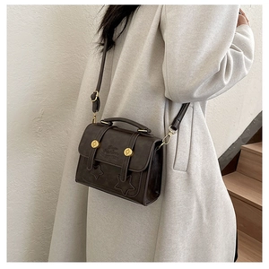 Detailed close-up of a vintage brown crossbody bag with gold hardware and star accents