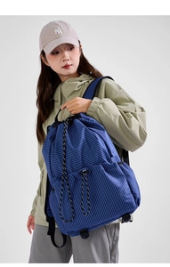 Detail of blue grid drawstring backpack showing lightweight nylon fabric and side straps