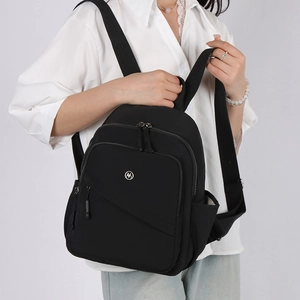 Detail of black nylon backpack featuring waterproof fabric and round metal logo detail