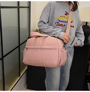Pink travel bag with large capacity and detachable shoulder strap shown on a model