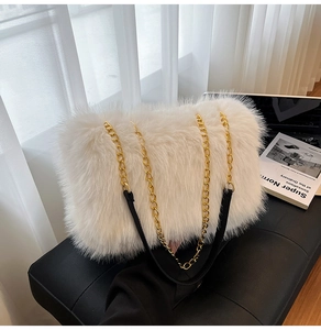 Detail of white faux fur tote bag with golden metal chain strap and leather shoulder pad