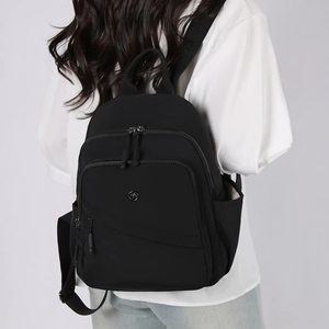 Rear view of model wearing a black nylon backpack with multi-zippered compartments