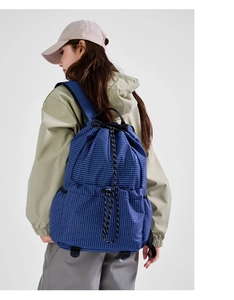 Detail of blue grid nylon drawstring backpack with bungee cord system on model