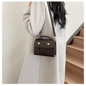 Detail of vintage brown crossbody bag featuring star stitching and golden metal rivets