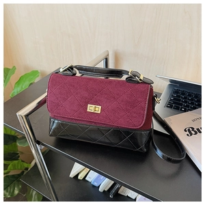 Détail d'un sac à bandoulière en cuir matelassé noir et daim bordeaux avec fermoir doré