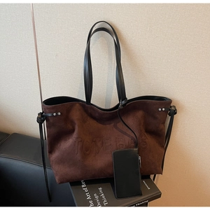 Dettaglio della borsa tote marrone scuro opaco con logo a rilievo e manici neri