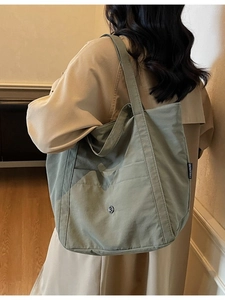 Olive green canvas tote bag for women shown with a model in a beige trench coat