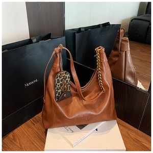 Braune Vintage-Hobo-Tasche mit Goldkette und Leoparden-Beutel auf gespiegeltem Hintergrund