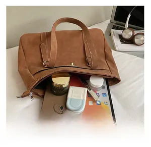 Gros plan sur la grande capacité intérieure avec tablette et essentiels dans un sac cabas brun