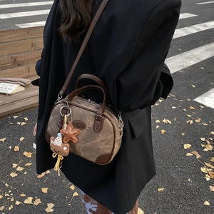 Vintage brown canvas Boston bag with leather straps and bear charm in autumn street setting