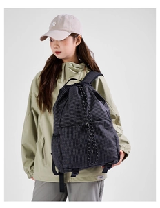 Detail of drawstring backpack featuring black and white grid pattern and woven cords