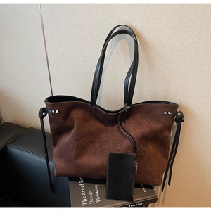 Dettaglio della borsa tote in pelle scamosciata marrone con logo e nodi in pelle nera