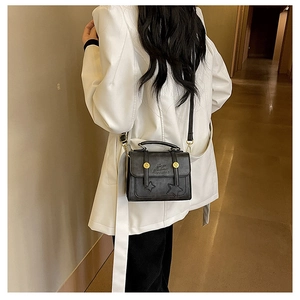 Detail of a vintage black leather crossbody bag with star relief and gold buttons
