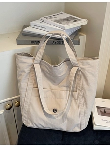Minimalist beige canvas tote bag with large front pocket and sturdy shoulder straps