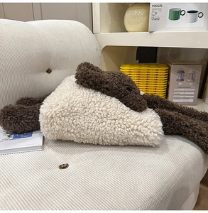 Dettaglio di un barboncino di peluche con gilet in pile crema su un divano bianco