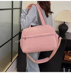 Model wearing a large pink travel bag with adjustable padded shoulder strap and side drawstring