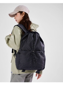 Detail of lightweight drawstring backpack with black and white grid pattern worn by model