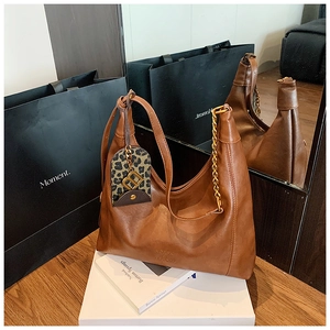 Detailansicht braune Hobo-Tasche aus mattem Leder mit Goldkette und Leoparden-Anhänger