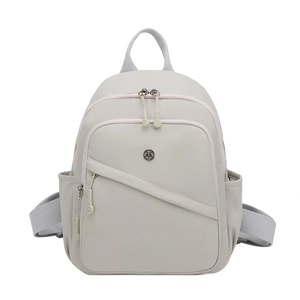 Detail of light grey nylon backpack showing front zip pocket and woven top handle