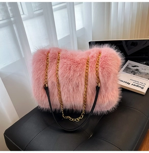 Close-up of pink faux fur tote bag with gold chain strap on a black leather seat