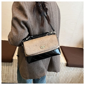 Détail du sac à bandoulière matelassé bicolore avec fermoir doré porté par un mannequin