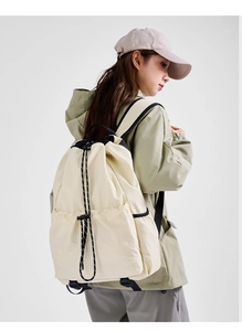 Macro shot of beige drawstring backpack showing ripstop nylon fabric and black cord detail