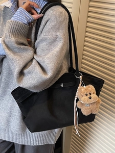 Minimalist black bucket tote bag with vintage texture and cute plush dog pendant charm