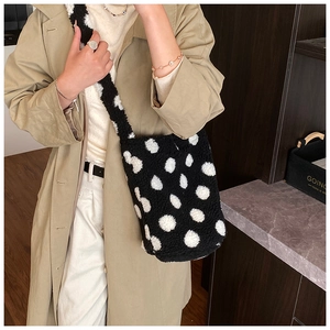 Detail of plush bucket bag with black and white polka dots and wide shoulder strap