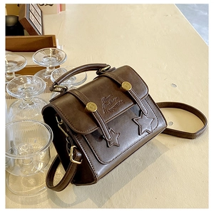 Detail of vintage brown PU leather bag with embossed text and stars decoration