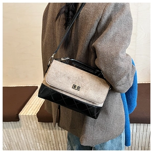 Détail du sac bandoulière matelassé bicolore avec fermoir doré sur une veste de tailleur
