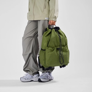 Detail view of grass green grid texture fabric and side pocket on drawstring backpack