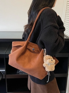Vintage brown suede tote bag with plush puppy charm shown in a warm lifestyle setting