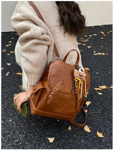 Brown vintage leather backpack with buckle detail and cute bear pendant outdoor view
