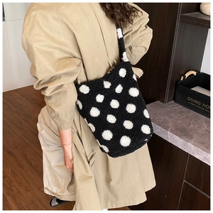 Detailed view of plush black and white polka dot bucket bag with soft lamb wool texture