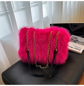 Close-up of bright pink faux fur tote bag with gold metal chain strap on leather seat