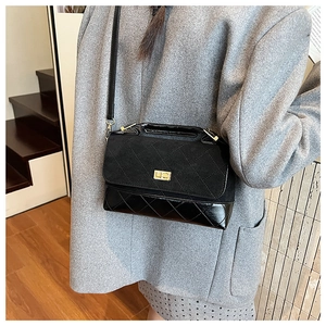 Détail du sac bandoulière matelassé noir avec textures en daim et fermoir doré tournant