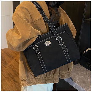 Detail view of large black tote bag featuring white contrast stitching and silver buckles
