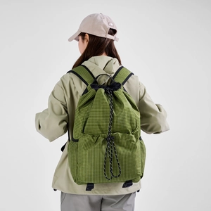 Rear view of a model wearing a green checkered drawstring backpack with side pockets