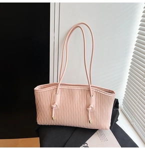 Détail d'un sac cabas rose clair avec texture plissée verticale et accents en métal doré