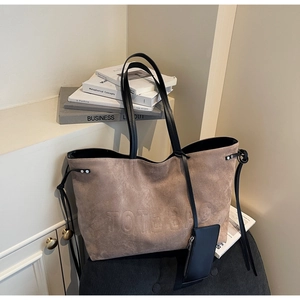 Dettaglio della borsa tote in pelle scamosciata taupe con goffratura e manici in pelle nera