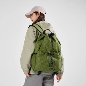 Green grid drawstring backpack with adjustable straps worn by a model in studio