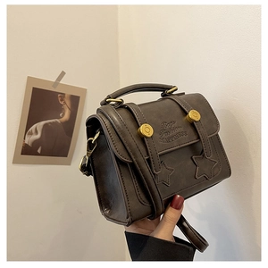 Detail of vintage brown leather bag featuring star embossing and gold circular hardware