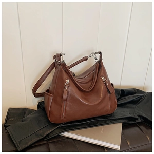 Detail view of caramel brown leather hobo bag with dual zipper pockets and silver hardware