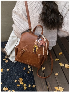 Detail view of a vintage brown mini backpack with decorative buckle and plush bear charm