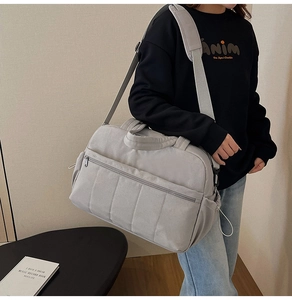 Detail of grey travel crossbody bag with wide shoulder strap and spacious pockets