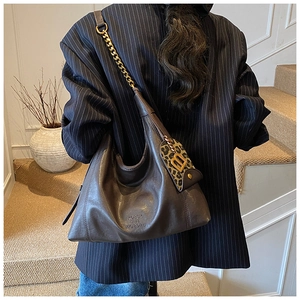 Details einer dunkelbraunen Ledertasche mit goldener Kette und B-Logo-Anhänger