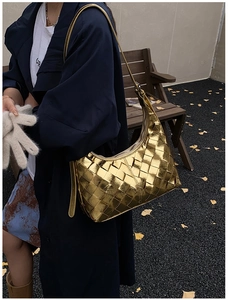 Detail der metallisch goldenen geflochtenen Hobo-Tasche mit Textur und verstellbarem Gurt