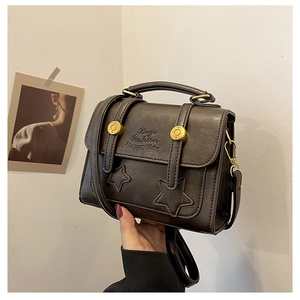 Detail of vintage brown leather crossbody bag featuring star patterns and gold studs
