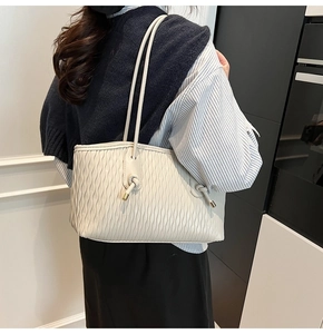 Détail d'un sac cabas plissé beige avec fines bretelles et décor de nœuds sur un mannequin